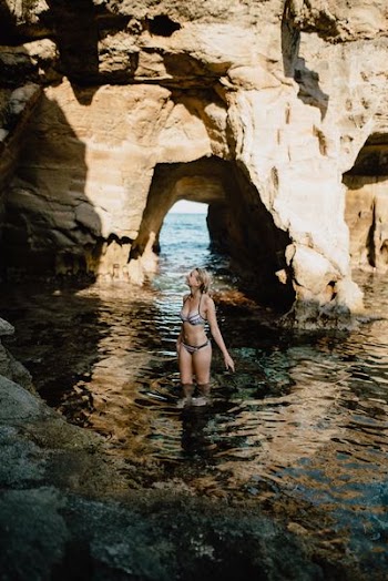 woman on sea beside rock formation