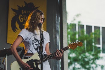 Woman on Stage Playing Electric Guitar and Facing Microphone
