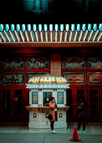 Woman On The Phone Standing In Front Of A Ticket Booth