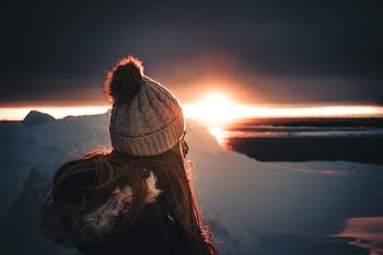 woman on top of mountain looking at sunset