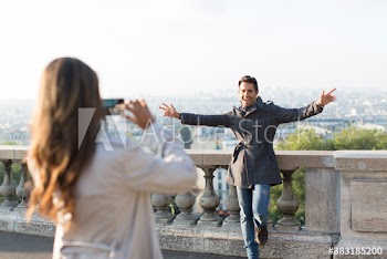 Woman photographing playful boyfriend, Montmartre, Paris, France