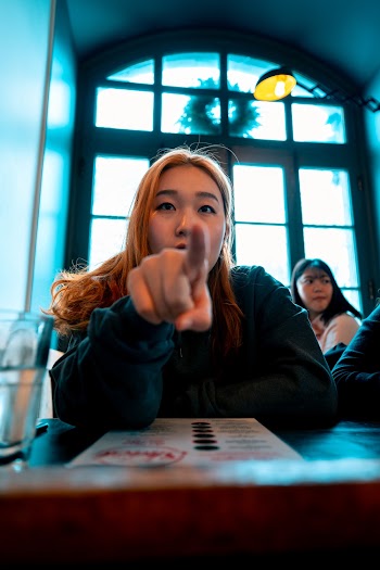 Woman Pointing in Her Front While Sitting Beside Table