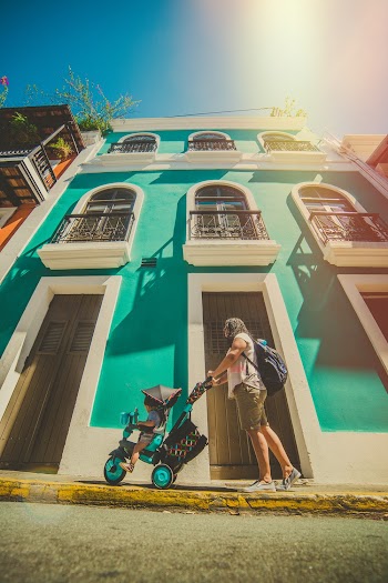 Woman Pushing Baby on Stroller in front of White and Green Building