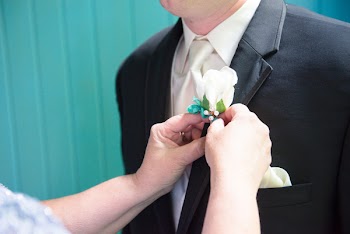 Woman Putting Boutonniere On Man's Suit