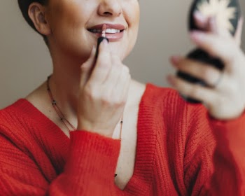 Woman Putting Lipstick While Using Press Powder Mirror