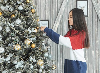 Woman Putting Ornaments on Christmas Tree