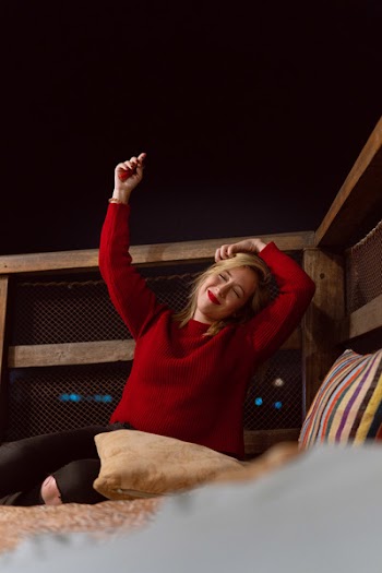 Woman Raising Her Arms While Leaning on Brown Handrail