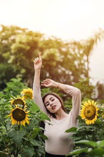 woman raising her hand surround by sunflowers during daytime