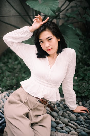 Woman Raising Her Right Hand Sitting on Pebbles