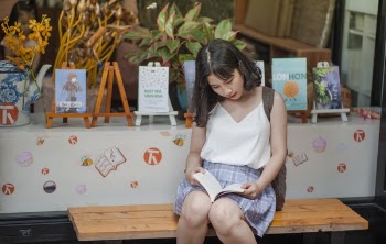 Woman Reading a Book While Sitting on a Bench