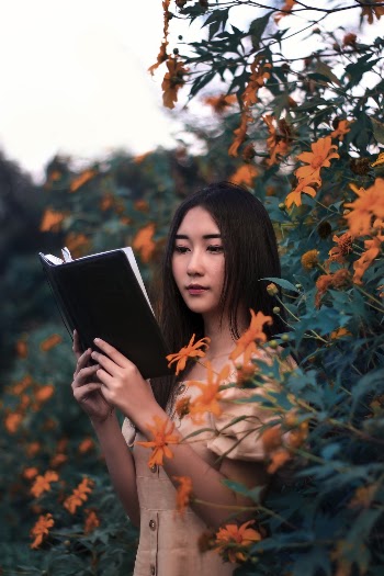 Woman Reading Book Surrounded by Plants