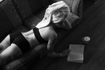 Woman Reading Book While Lying in Sofa