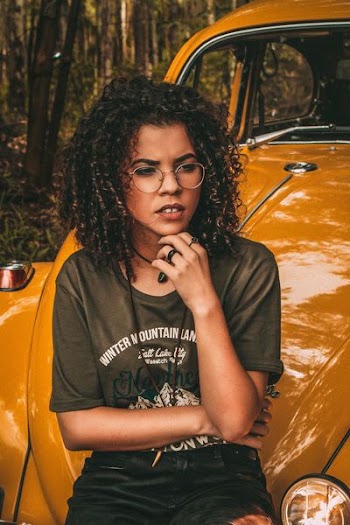 woman resting chin sitting on yellow Volkswagen Beetles hood