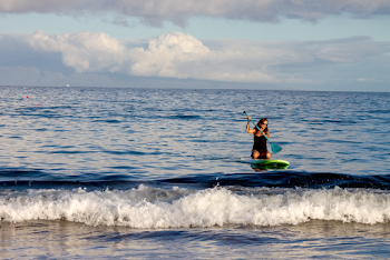 Woman Riding Green Surfboard Using Paddle