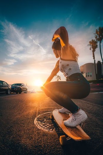 woman riding longboard on concrete street during daytime
