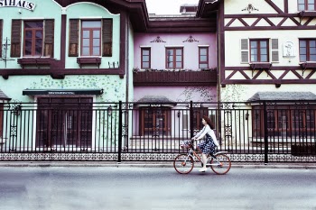 Woman Riding on Bicycle Near Concrete Houses