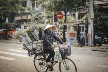 Woman Riding on Bike With Flowers on Her Bicycle Luggage Rack