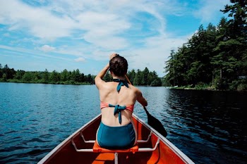 woman riding on boat while paddling under blue sky during daytime