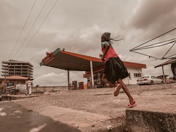 Woman Running Near Red and White Gasoline Station