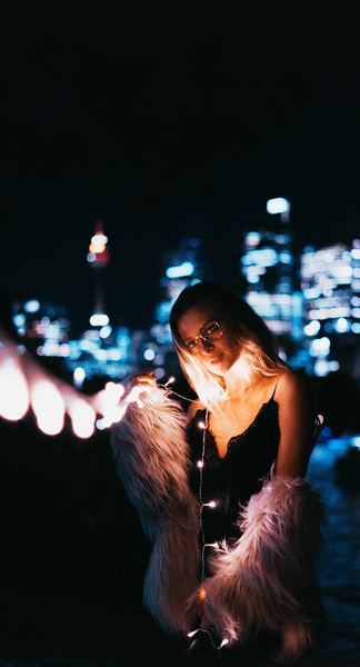 woman's in black dress holding white string lights