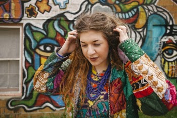 Woman Scathing Her Head in front of a graffiti wall