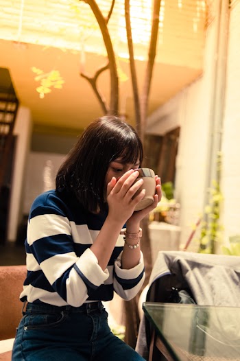 Woman Seated Outside Drinking from a Brown Bowl
