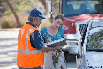 Woman signing paperwork for male roadside assistance mechanic