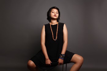 Woman Siting on a Stool in Front of a Gray Background