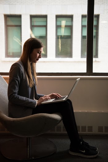 Woman Sits and Use Laptop Computer Near Window
