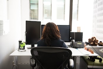 Woman Sits on Black Rolling Armchair