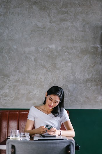 Woman Sits on Chair Holding Smartphone