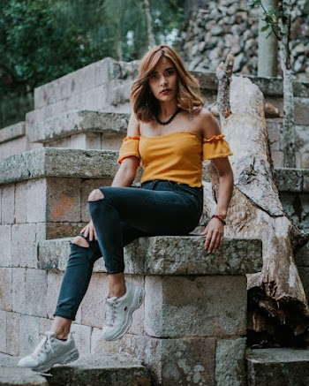 Woman Sits on Concrete Chair Beside Tree Trunk