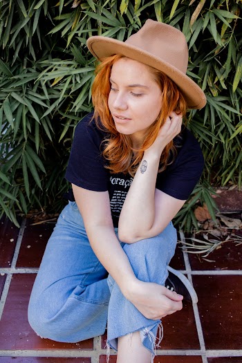 Woman Sits on Floor Wearing Hat