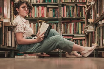 Woman Sits on the Floor Inside Library