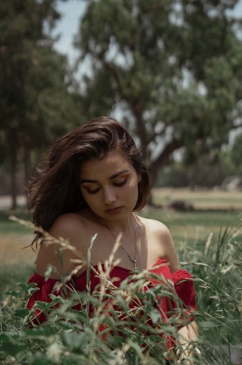 Woman Sitting and Looking Down on Green Field