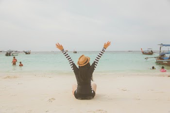 Woman Sitting at the Beach Near Boats and People during Day