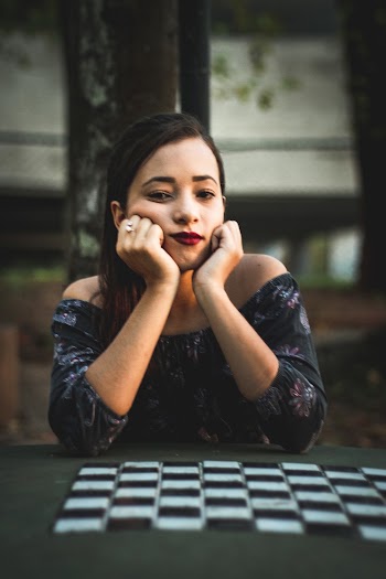 Woman Sitting Beside Chess Table With Hands on Chin