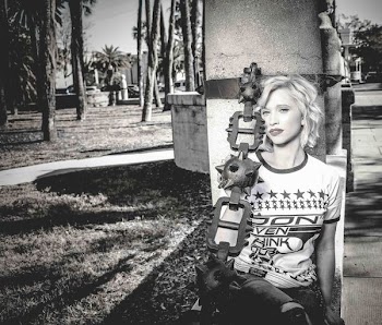 Woman Sitting Beside Gray Concrete Post Grayscale Photo
