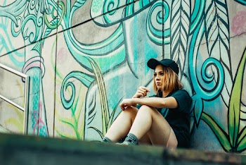 Woman Sitting Beside Mural Covered Wall