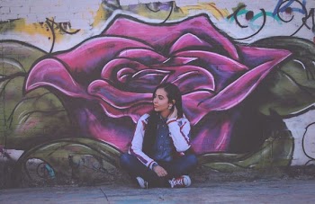 woman sitting beside purple flower wall painting