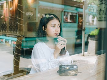 Woman Sitting Beside Table While Drinking