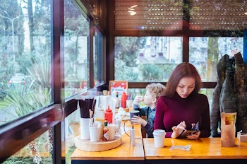Woman Sitting Beside Table While Using Phone