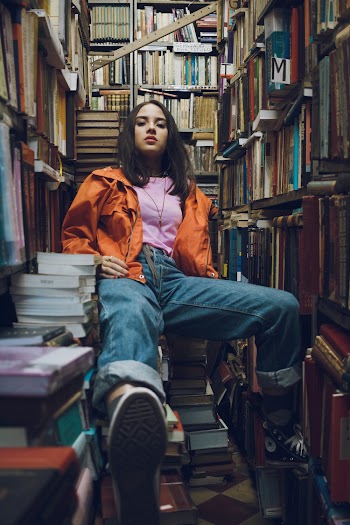 Woman Sitting Between Bookshelves