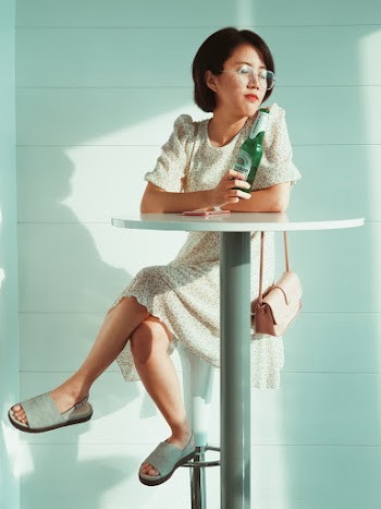 Woman Sitting by the Table Holding Bottle
