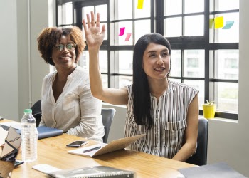 Woman Sitting by the Table Raising Her Hand