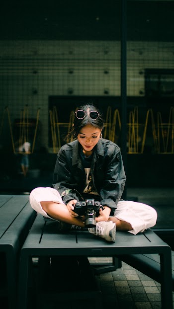 Woman Sitting Down Looking Into A Dslr Camera