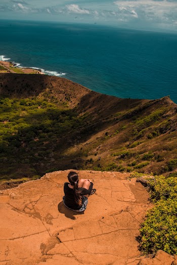 Woman Sitting Down on a Cliff looking at the Ocean