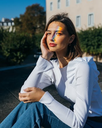 Woman Sitting Holding Her Face and Knee Beside Building