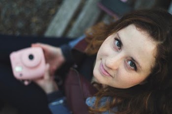 woman sitting holding pink instant camera