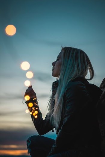 woman sitting holding string lights